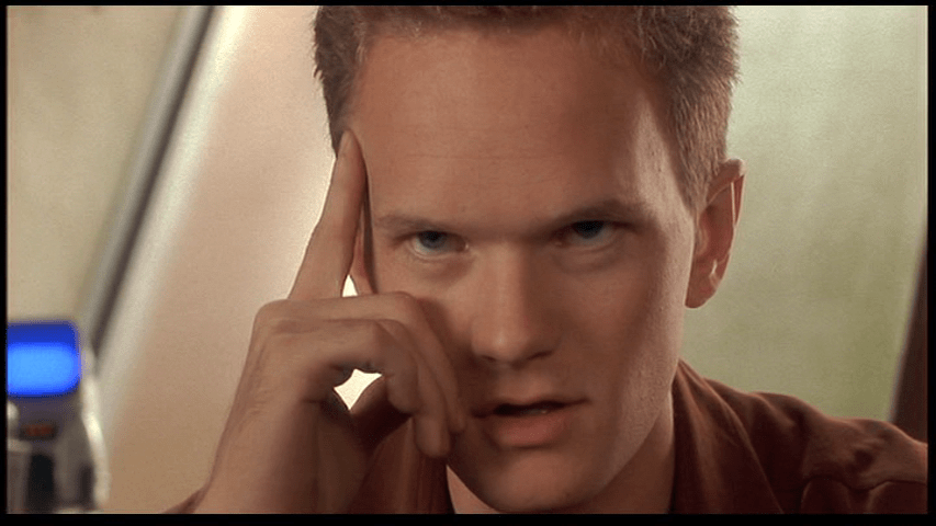 Close-up of Carl putting a finger on his temple and concentrating intently as he looks offscreen