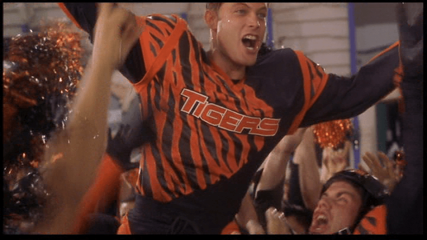 Medium shot of Johnny celebrating his victory in an orange and black uniform with the team name "Tigers" emblazoned across the chest