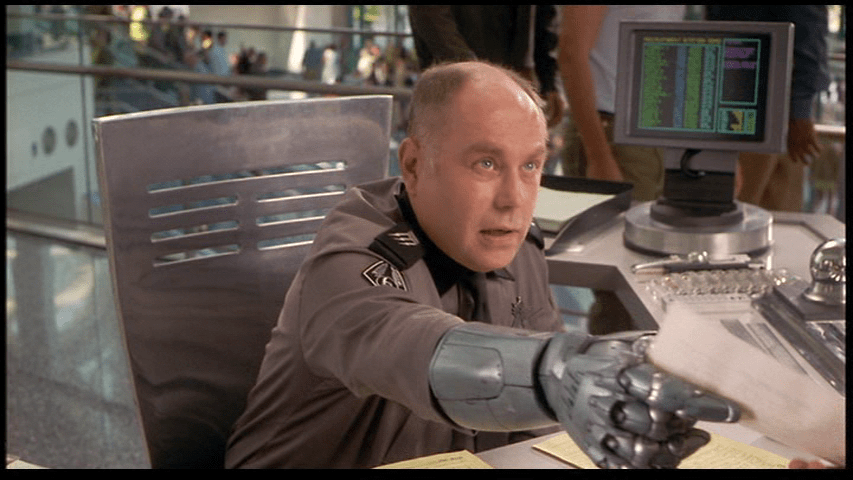 Medium shot of a recruiting sergeant using his robotic hand to give Carl, who is offscreen, a piece of paper