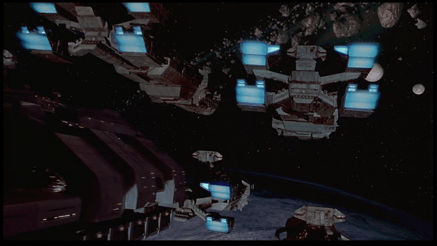 A fleet of spaceships navigate through an asteroid field in long shot