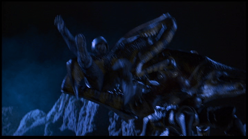 Long shot of a reporter in a military uniform being held aloft by a giant insect