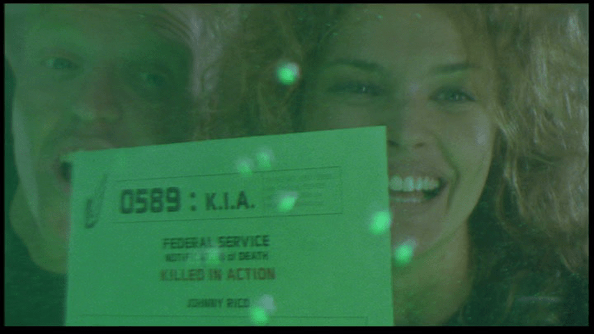 Close-up of Dizzy and Ace Levy (Jake Busey) holding up a piece of paper identifying Johnny as K.I.A. to the side of the tank