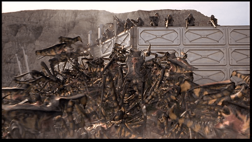 Bug warriors scramble over top of their fallen comrades corpses to swarm the walls of a base defended by humans