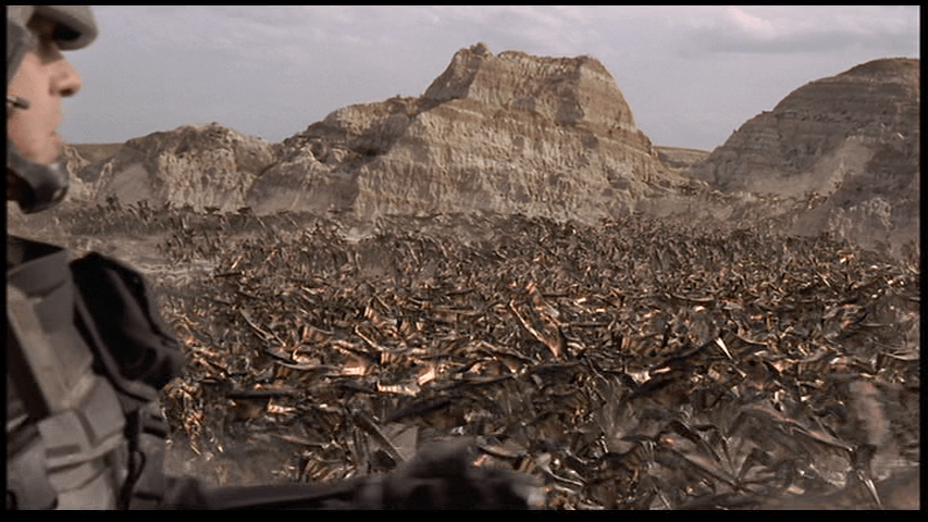 A soldier on the left side of the screen looks out over thousands of Bug attackers