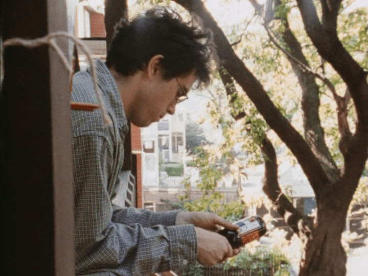 Medium shot of Andrew Bujalski's Mitchell leaning over a balcony contemplating a bottle of beer