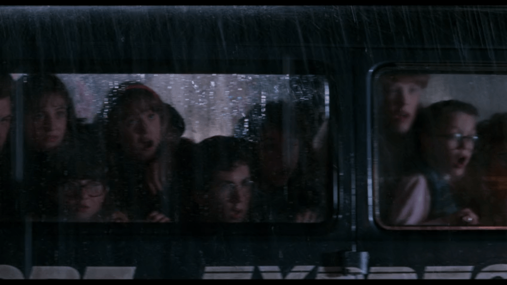 Continuation of the previous shot: a crowd of children in the middle seats of the van also look open-mouthed at the sight outside it