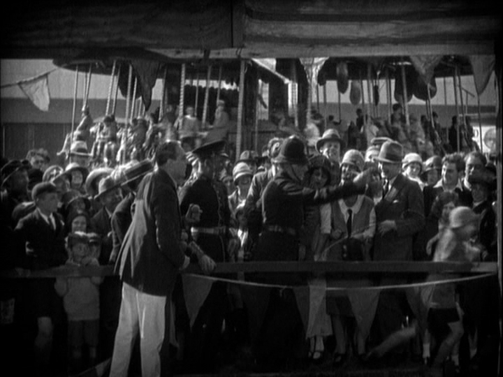 Long shot of the police officer from the previous image shooing the egg-throwing boys away