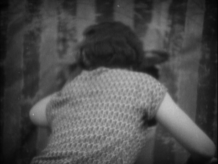 Medium shot of Mabel peering through a flap in the carnival tent that the fight is taking place in