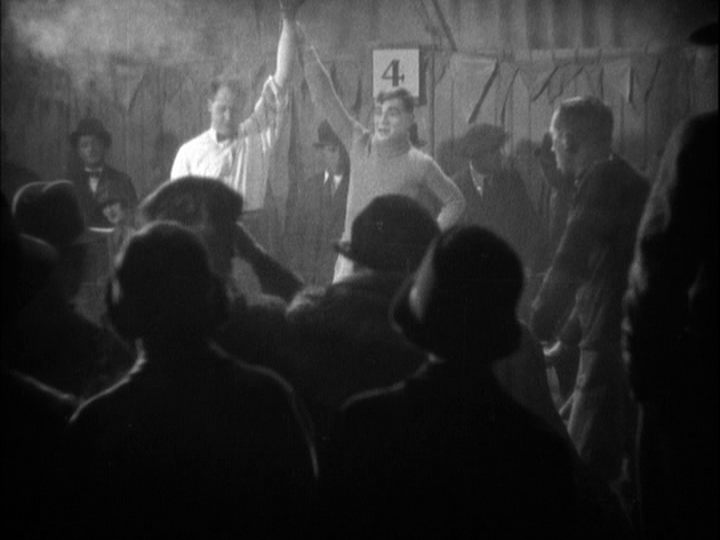 Medium long shot of the referee holding Corby's hand out, victorious