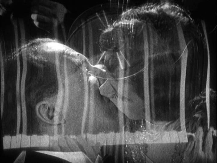 An image of Corby kissing Mabel is superimposed over elongated piano keys and a turntable