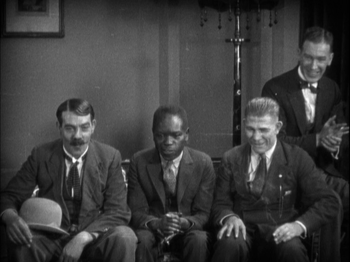 Medium shot of Sander's friends staring intently at the champagne