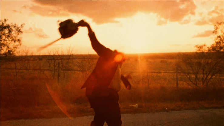 Medium shot of a man swinging a chain saw as though it were a dance partner in front of a sunset