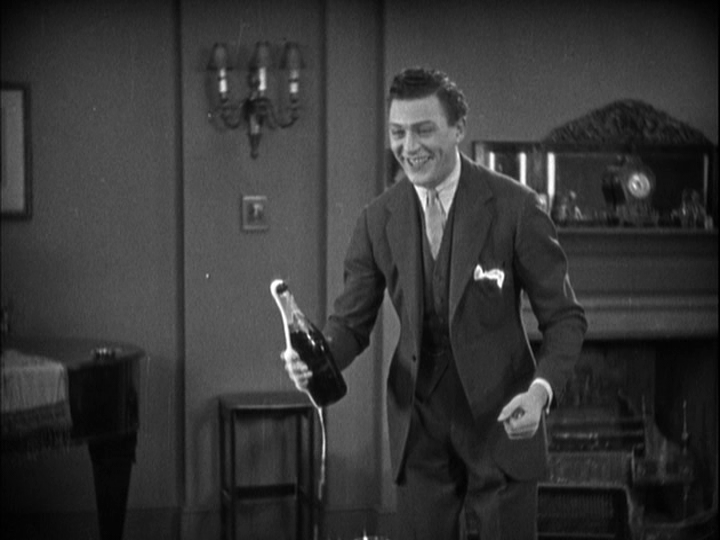 Medium shot of Sander holding an uncorked bottle of champagne which is bubbling over