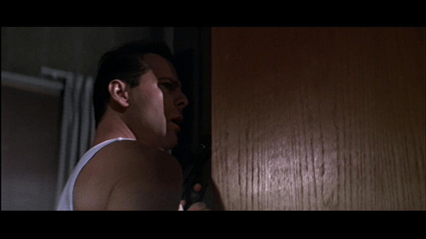 Medium shot of McClane peaking through a door