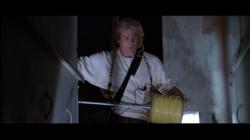 Medium shot of Heinrich (Gary Roberts) unspooling yellow wire