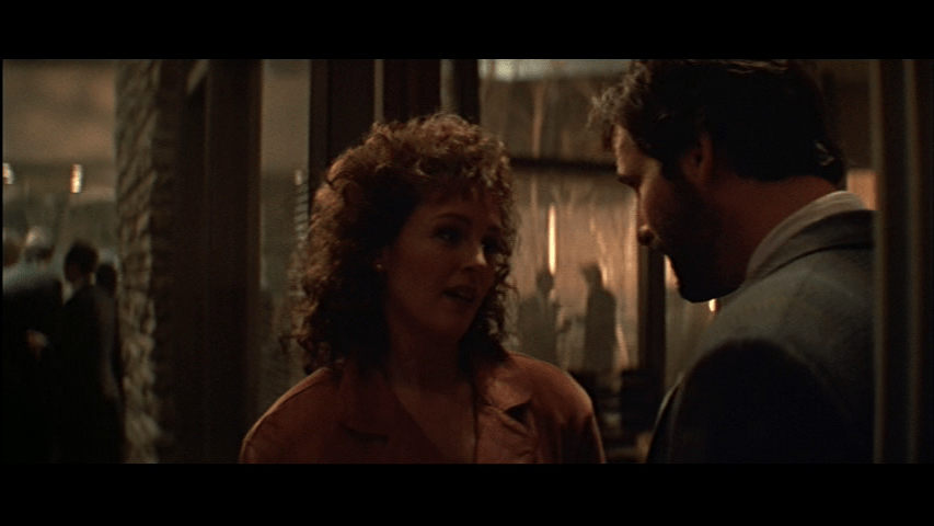 Ellis sweet talks Holly, who occupies the middle of the frame, from the right third of it