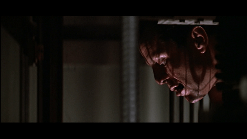 Close-up of McClane in the right third of the frame peering down into an elevator