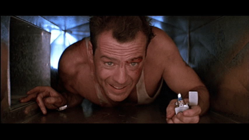 Close-up of McClane crawling through an air vent lit by the lighter he holds in the foreground