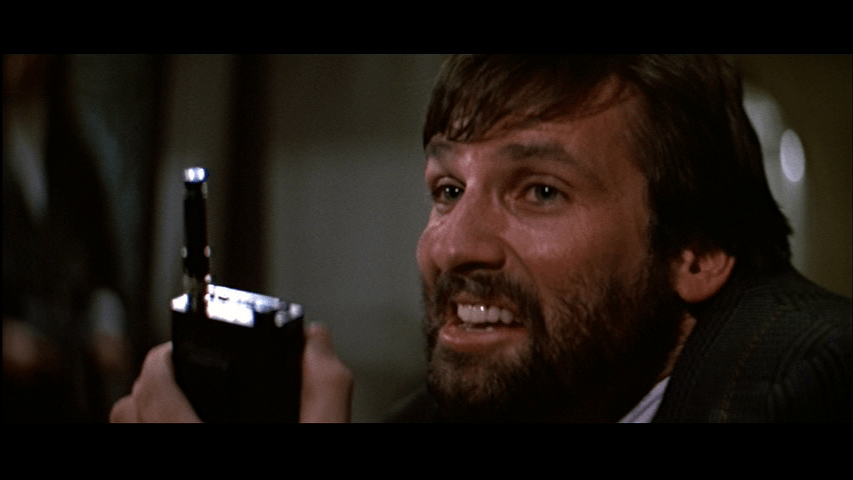 Close-up of Ellis holding a walkie-talkie and looking very foolish