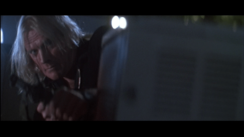 Karl aims his gun from the left third of the frame