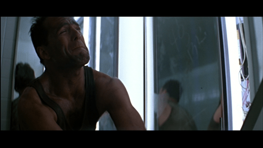 Medium close-up of McClane wincing in the left half of the frame