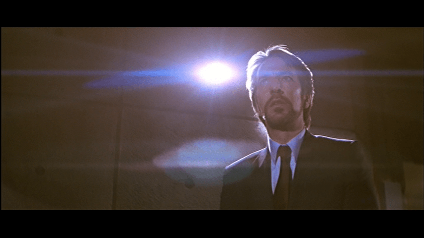 Low-angle medium close-up of Gruber, who occupies the right third of the frame