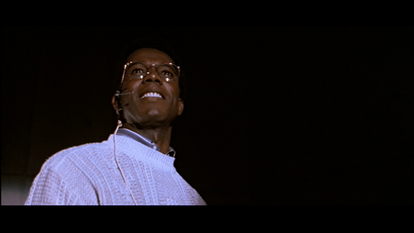 Low-angle medium close-up of Theo, who occupies the left half of the frame