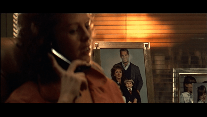 Continuation of the previous shot: Holly turns to the camera and the focus begins to shift from the photo to her