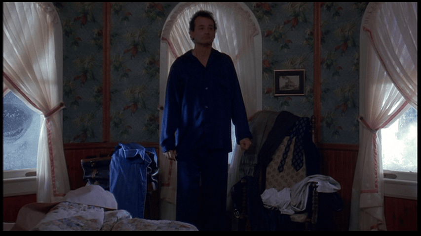 Medium long shot of Bill Murray's Phil Connors standing in the middle of the room of his Bed & Breakfast the morning he resolves to make the most of eternity