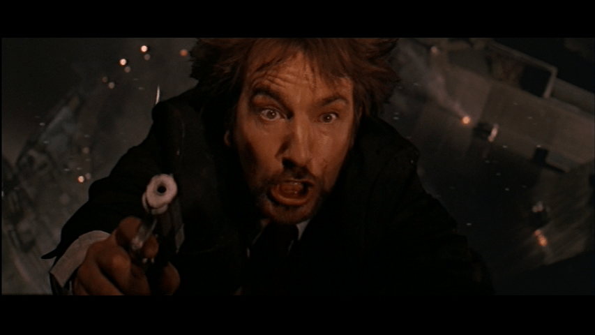 Overhead close-up of Gruber brandishing a gun and looking surprised as he begins to fall