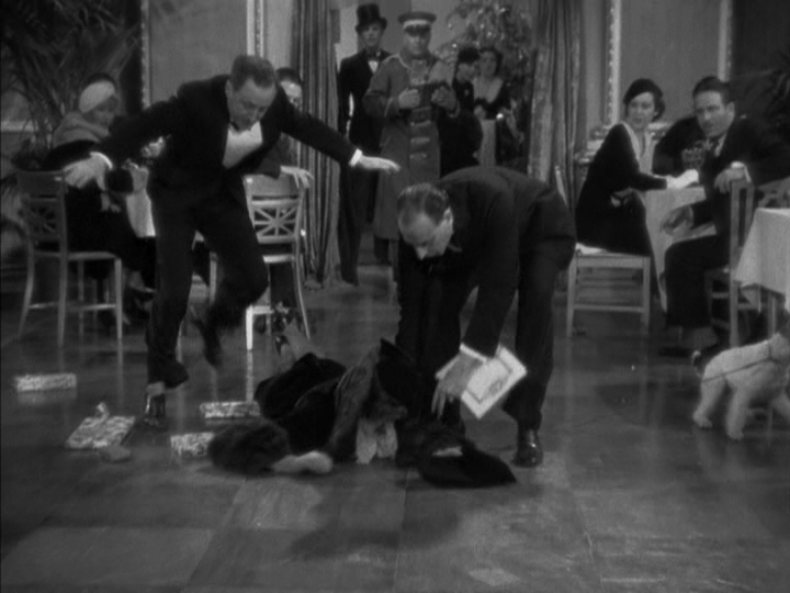 The two waiters begin to help up Nora, who sprawls face-down on the floor
