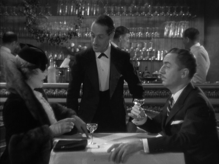 Medium shot of Nora pointing to the spot on the table where she finds their waiter to line up the five martinis she's ordering as Nick looks on surprised