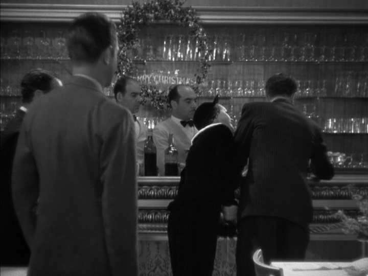 Medium long shot of Dorothy leaning over to Nick on the right side of the frame and her fiancé Tommy (Henry Wadsworth) watches from the left side of the frame, all of them with their backs to the camera