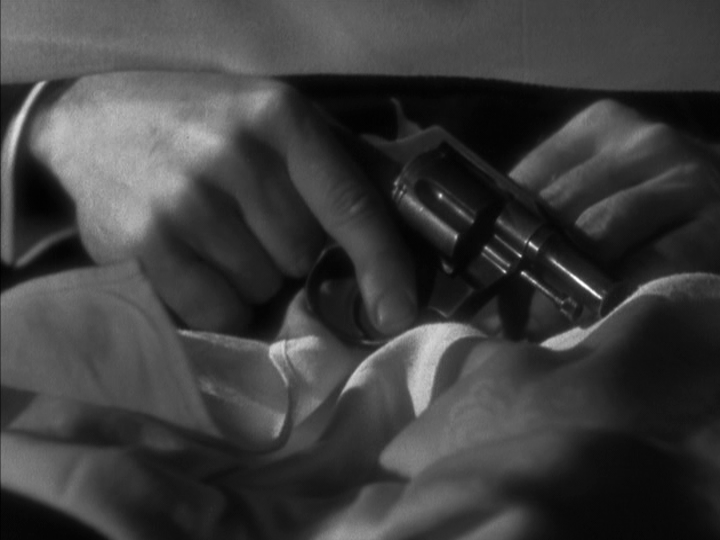 Close-up of hands pulling a gun out from under the table