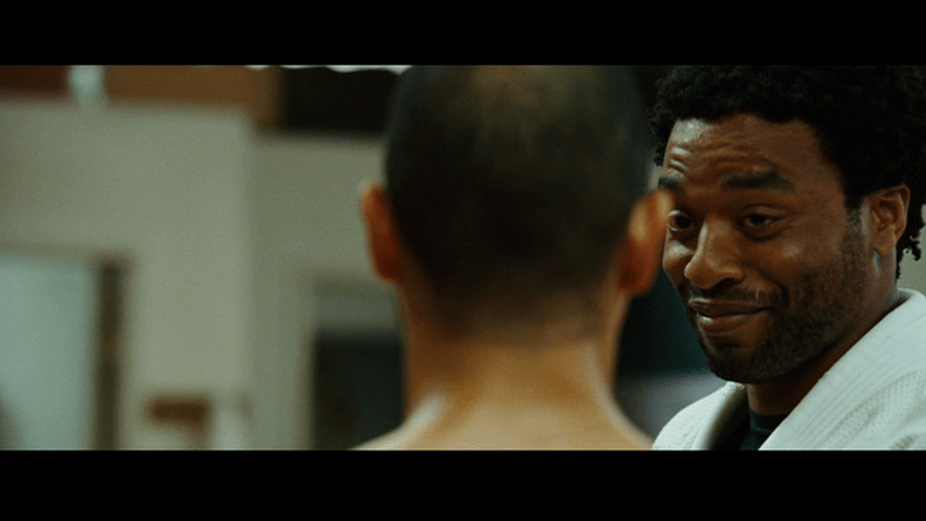 Close-up of Mike looking at Snowflake, who is out of focus with his back to the camera, in the right half of the frame