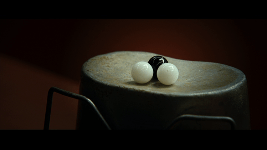 Close-up of three marbles resting in the concave bottom of an upturned tin cup