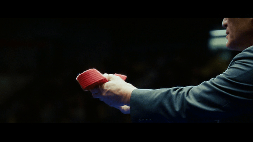 Continuation of the previous shot: the Professor holds the belt out to Mike, who remains offscreen