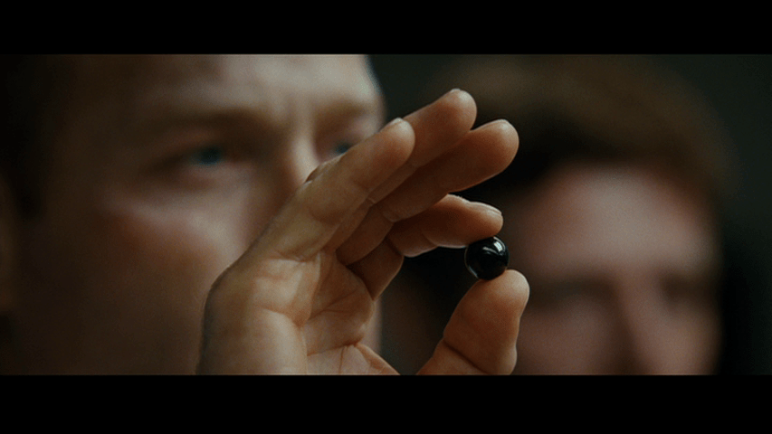 Continuation of the previous shot: the focus has shifted to the black marble that the fighter has held up in the foreground in front of his face