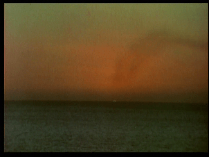Long shot of the last light from an ocean horizon sunset suddenly flashing green