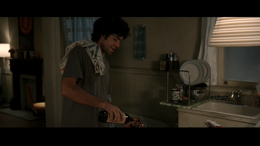 Medium shot of Nate pouring wine from the left third of the frame