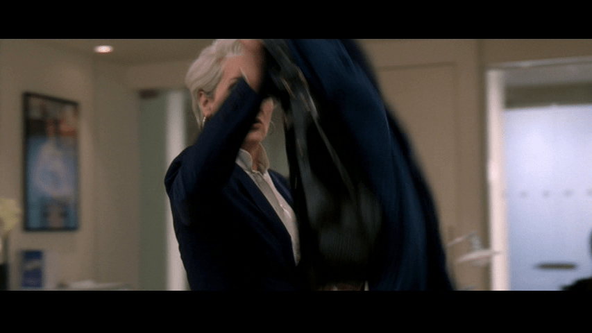 Medium shot of Miranda throwing her coat on Andy's desk