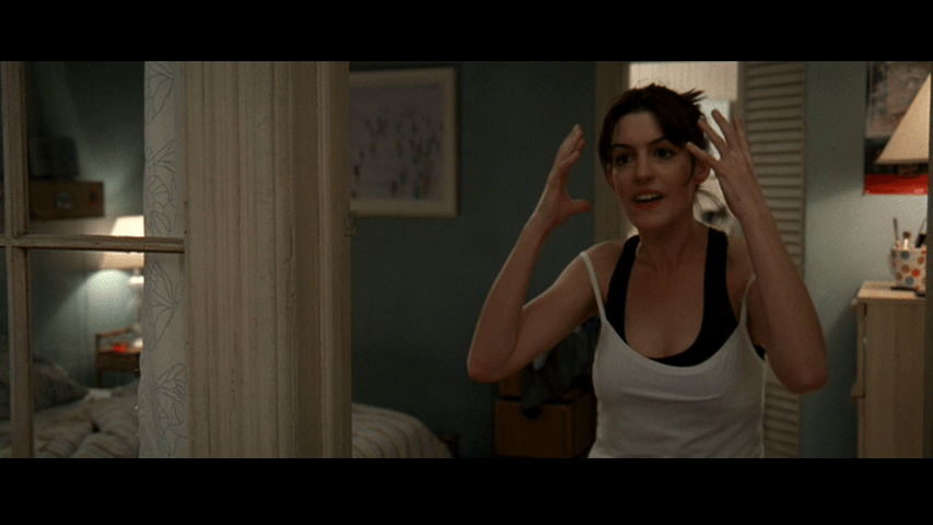 Continuation of the previous image: Andy uses her hands to express frustration from a position much closer to the camera in the right third of the frame