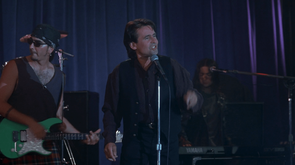 Medium long shot of Davy Jones singing "Girl" backed by a grunge band