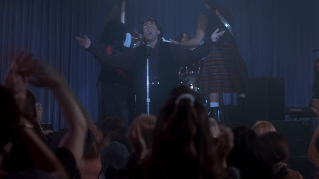 Long shot of Jones ending his song on a high note as the kids go wild in the foreground