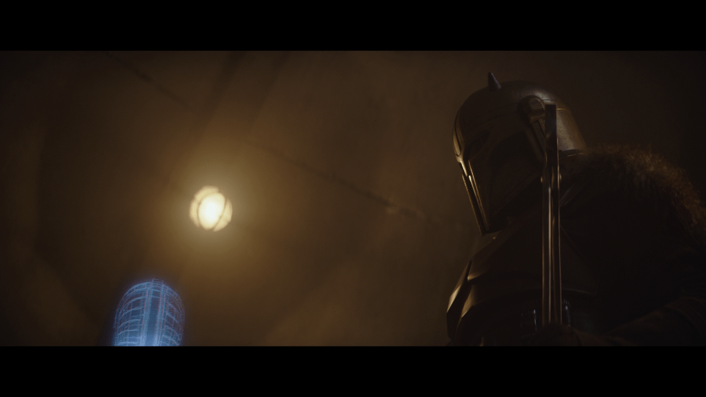 Low-angle long shot of the Armorer looking at a hologram of a pauldron