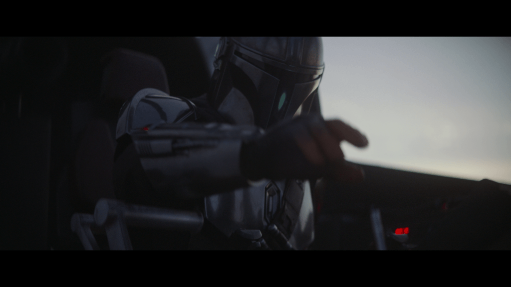 Medium close-up of Mando reaching toward something out of focus in the foreground