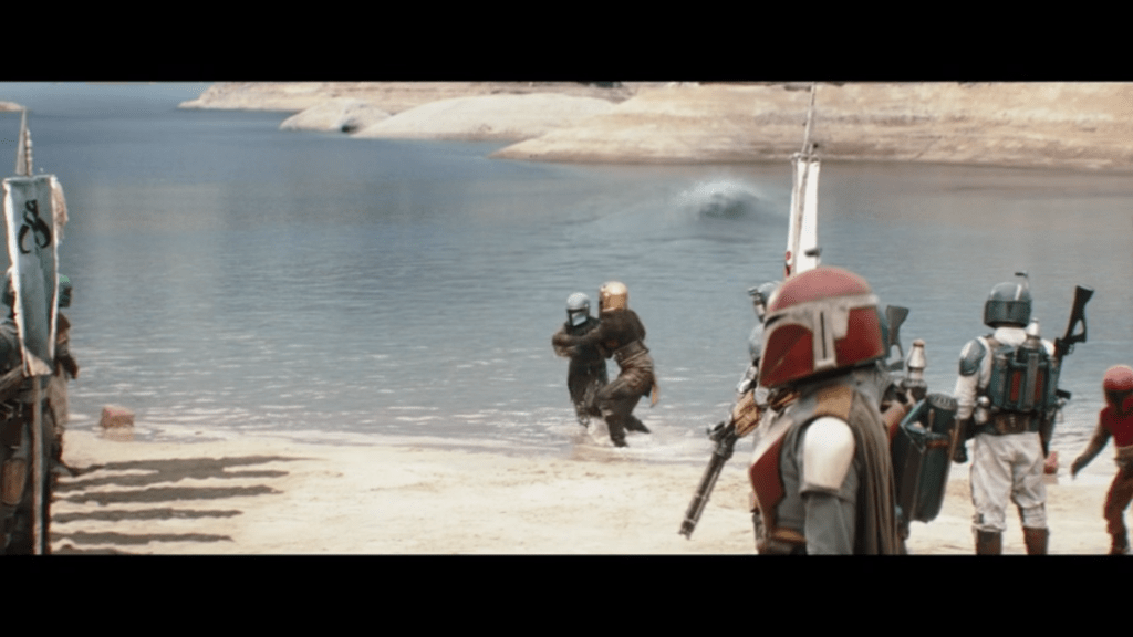 Long shot of the Armorer whisking Ragnar Vizsla away from the approaching Dinosaur Turtle
