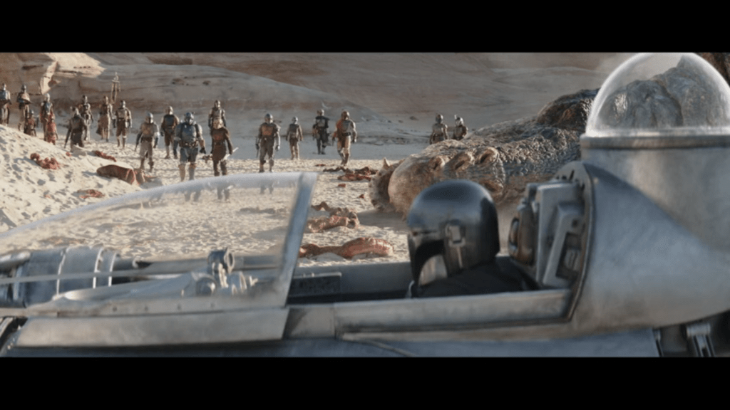 Medium shot of Mando in his ship in front of the dead Dinosaur Turtle and a crowd of Mandalorians