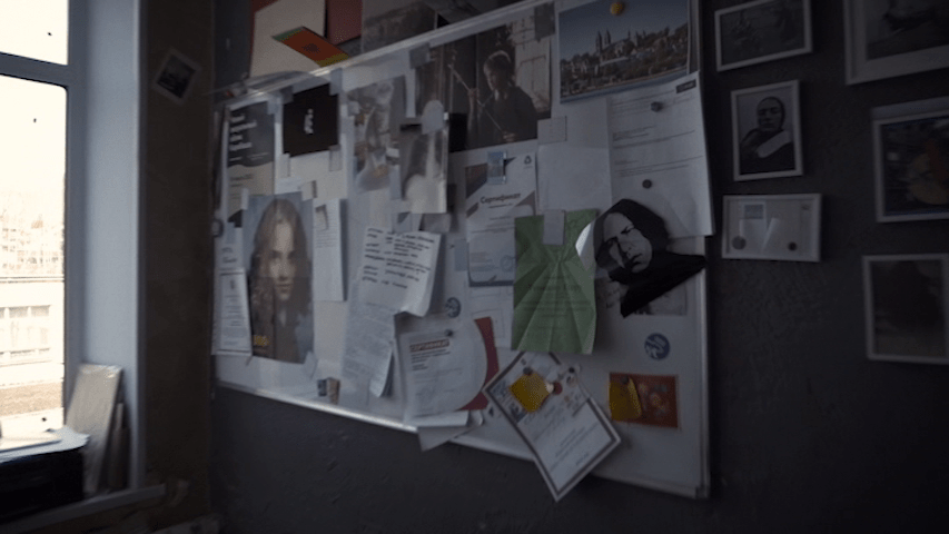 Medium shot of a whiteboard covered in flyers and pictures, including ones of Harry, Hermione Granger, and Severus Snape