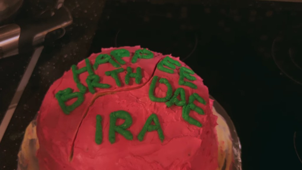 Close-up of a cake with "Happee Birthdae Ira" written on it in green icing